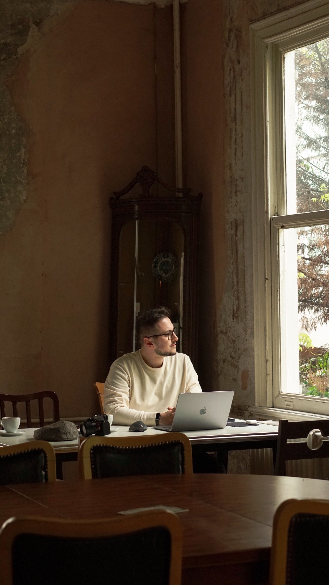 A UK company director working at a laptop by a tall window